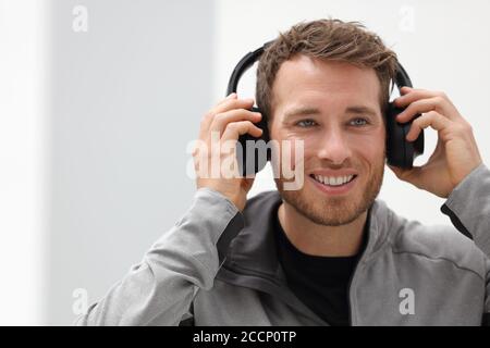 Man putting on headphones to listen to music mobile phone app. Happy smiling young urban person wearing headset sing smartphone mobile app listening Stock Photo