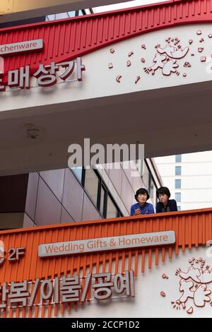 Two women chatting at a balcony. Wholesale market. Wedding gifts and homeware section. They are friends or colleagues. Serious faces. Seoul, Korea Stock Photo