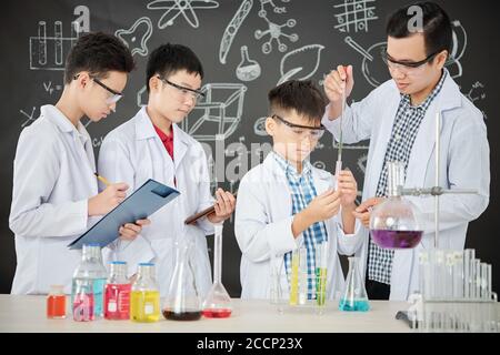 Students and teacher conducting experiment Stock Photo
