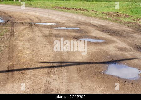 Puddles and mud on the gravel road after rain on countryside Stock Photo