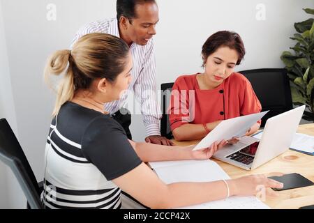 Business executives gathered at office table Stock Photo