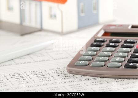 Pocket calculator with pen on financial analysis sheets with house model, real estate investment or poroperty costs concept, selective focus Stock Photo