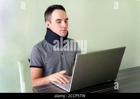 neck support on the prosthesis. fracture of the cervical vertebrae. Treatment of neck pain. Man freelancer in a cervical collar neck brace working Stock Photo