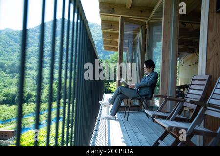 Businessman Reading a Book on the Balcony Stock Photo