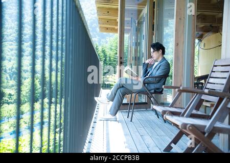 Businessman Reading a Book on the Balcony Stock Photo