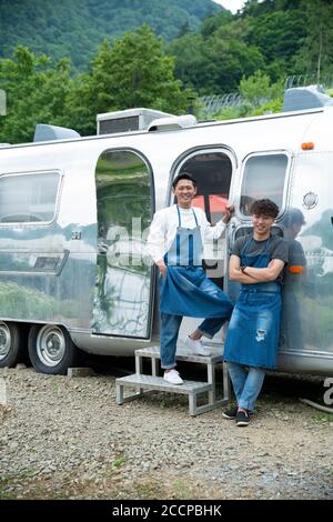 Young Male Staffs Standing in front of Food Truck Stock Photo