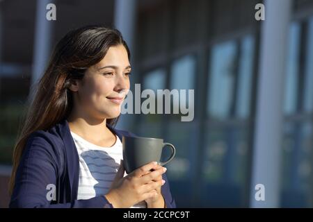 Woman drinks coffee in a terrace looking away a sunny day Stock Photo