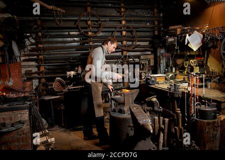 Blacksmith working metal with hammer on the anvil in the forge Stock Photo