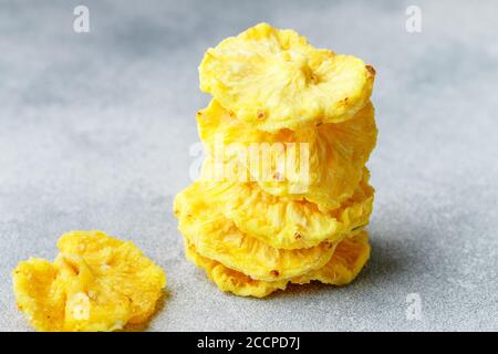 Dried yellow pineapple rings on a grey concrete or stone background. Useful Healthy snack. Selective focus, copy space Stock Photo