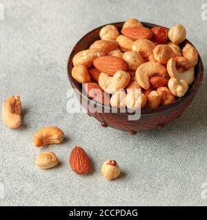 Healthy mix of different nuts in a bowl on a gray concrete or stone background. Almonds, hazelnuts, cashews. A Useful snack. Good nutrition. Selective Stock Photo
