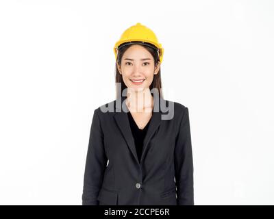 Young Asian businesswoman smiling wearing black suit and yellow safety helmet. Portrait of female engineer looking confident isolated on white backgro Stock Photo