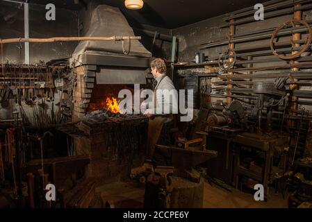 Blacksmith heating metal rod in fire Stock Photo