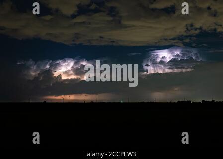 Two supercell thunderstorms are illuminated by lightning flashes Stock Photo