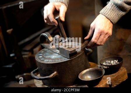 Coinage craftsman stamping coins with hammer and anvil. Vintage style handicraft concept Stock Photo