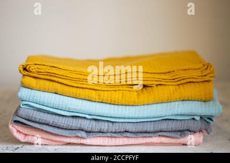 Pink, blue, mustard, grey muslin fabrics, diapers on a white background closeup Stock Photo