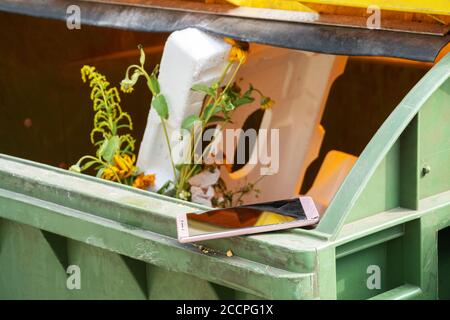phone with a broken screen lies on an open trash can Stock Photo