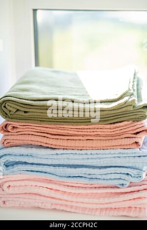 Colorful blankets on the windowsill in a stack, closeup Stock Photo