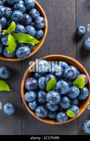 Fresh organic blueberry in bowl on wooden background. Healthy food concept, juicy wild forest berries.