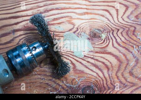 the master cleans an electric drill with a metal brush on a wooden surface Stock Photo