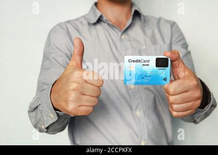 Man holding credit card with built-in fingerprint scanner and showing thumb up. Concept of safe payment without pin code. Biometric banking. Man is Stock Photo