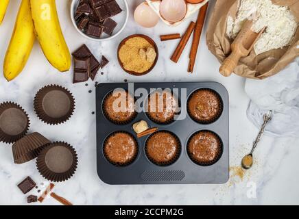 Preparation homemade muffins with banana and chocolate for Breakfast. Ingredients on the table - wheat flour, eggs, brown sugar, chocolate chips, fres Stock Photo