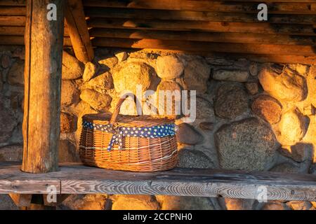 decorative wicker basket on a wooden table against a stone wall background Stock Photo