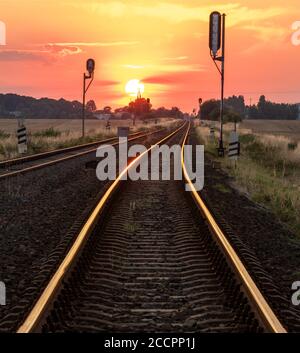 sun is setting over the railroad tracks Stock Photo