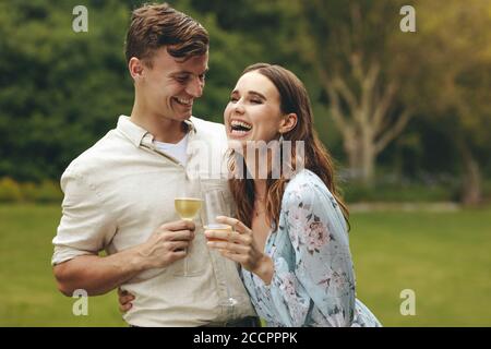 Beautiful couple in love with champagne at park. Beautiful woman and handsome man having a great time at picnic. Stock Photo