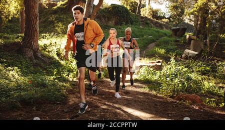 Athletes running on mountain trail. Men and women running a cross country marathon race. Stock Photo