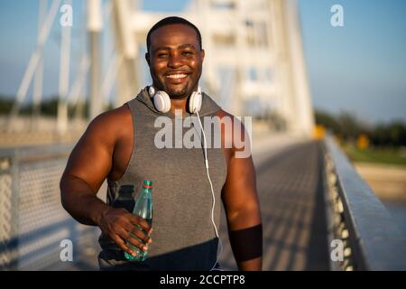 Portrait of young cheerful african-american man in sports clothing who is looking at camera and smiling. Stock Photo