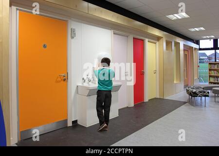A young boy in school uniform washes his hands in a new school library building, Nottingham, UK. Stock Photo