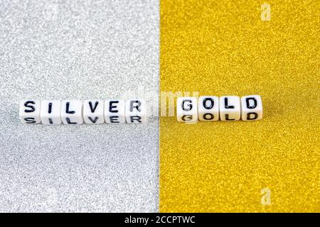 silver  and gold words formed by white dices with black letters  laying on silver and golden background, image split in two halves Stock Photo