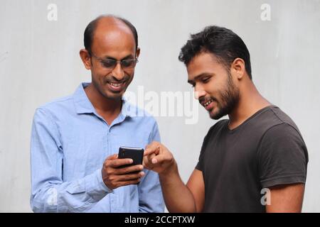 Asian father showing news feed on the phone to his son in happy mood with white background Stock Photo