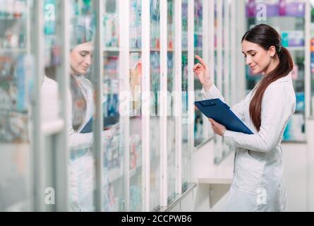 pharmacist chemist woman working in pharmacy drugstore with tablet. Stock Photo