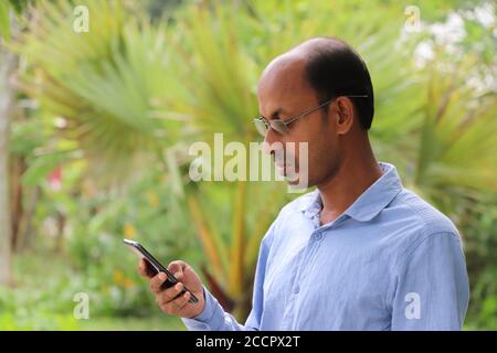 Casual Asian man using smartphone, reading messages on mobile phone screen Stock Photo