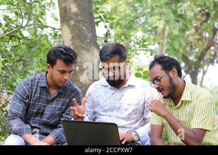 Two Asian students working on a research project on laptop with their mentor on college campus Stock Photo