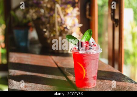 Cold raspberry juice with ice and leaf wooden top. Stock Photo