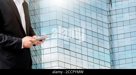 Hands of a businessman using digital tablet with skyscrapers buildings in the background. Stock Photo