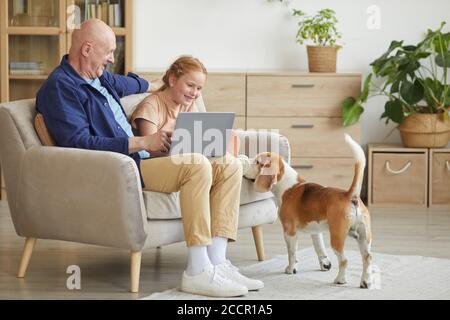 Full length portrait of modern senior man enjoying time at home with cure red haired girl and pet dog, copy space Stock Photo