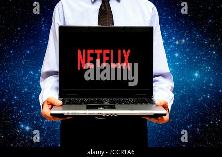 man holding a laptop with a logo of Netflix streaming service on the screen Stock Photo