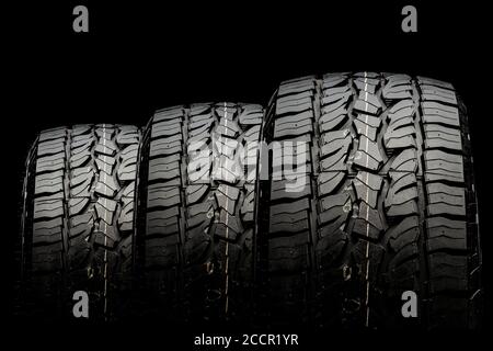 three tires in a row for SUVs and crossovers with powerful checkers and ground grabs close-up on a black background Stock Photo