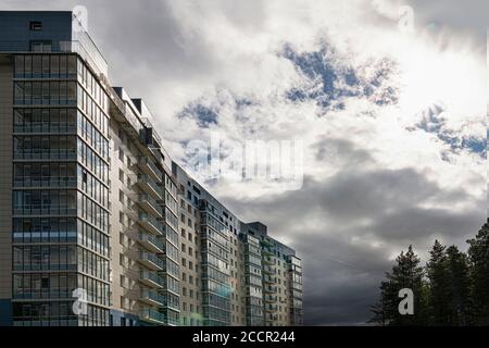 Krasnoyarsk, Russia, August 10, 2020: residential building with balconies against the dark sky, on the edge of the forest. Modern eco-friendly area Stock Photo