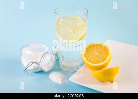 Baking soda in drinking glass with water and lemon juice, health benefits for digestive system concept. Light blue background. Stock Photo