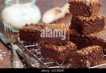 Fresh baked homemade vegan brownie with ground coconut and chocolate slices cut in square servings . Delicious American dessert. Selective focus Stock Photo