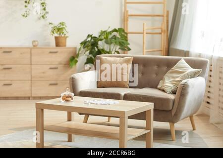 Warm toned background image of cozy home interior featuring comfortable beige sofa and coffee table, copy space Stock Photo
