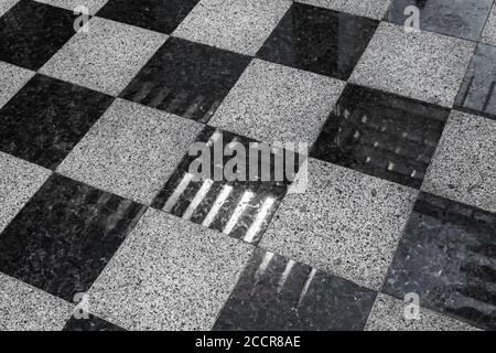 Shiny stone floor tiling with classical black and white checkered pattern and modern lights reflections Stock Photo