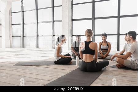 Fit young people relaxing and chatting before group fitness training in studio Stock Photo