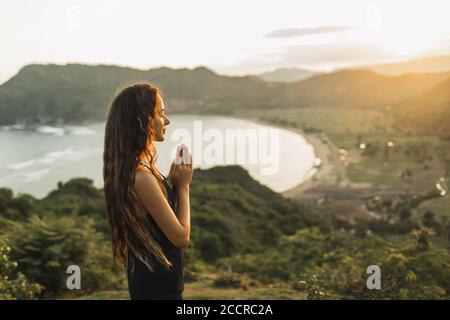 Woman praying alone at sunrise. Nature background. Spiritual and emotional concept. Sensitivity to nature Stock Photo