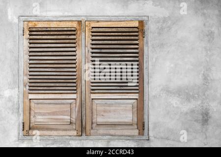 Window with closed wooden shutters. Gray concrete cement wall background. Stock Photo