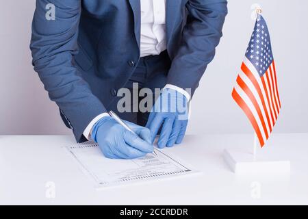 The general official voting during coronavirus pandemic COVID-19. A choice between candidates for president of US in 2020. Person fills out paper ball Stock Photo